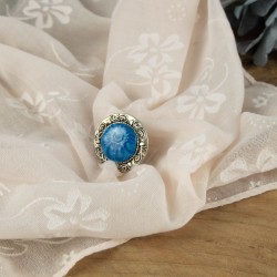 Une bague lumineuse posée sur un écrin végétal – le bleu profond révèle ses nuances sous la lumière