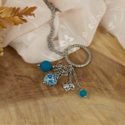 Zoom sur le cœur filigrane, la fleur et les perles artisanales.