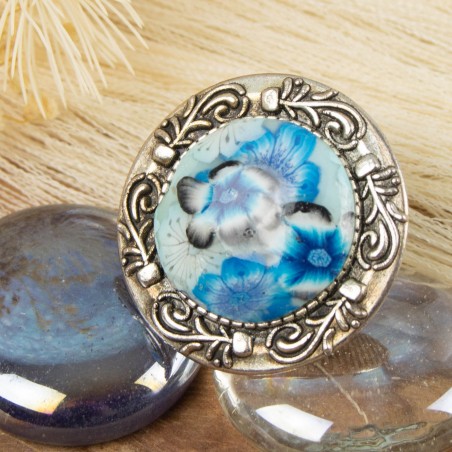 Zoom sur le cabochon fait main : motifs floraux et vernis éclatant, un bleu hypnotique.